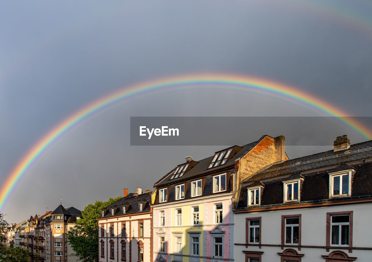 Rainbow over buildings in city against sky