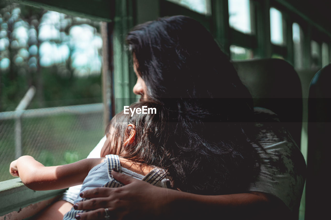 Side view of woman looking through window in a train