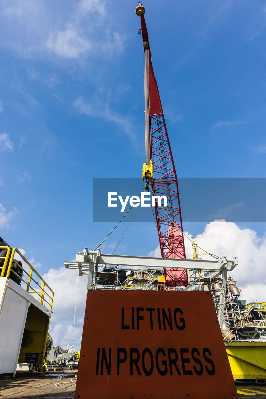 LOW ANGLE VIEW OF CRANES AGAINST YELLOW SKY