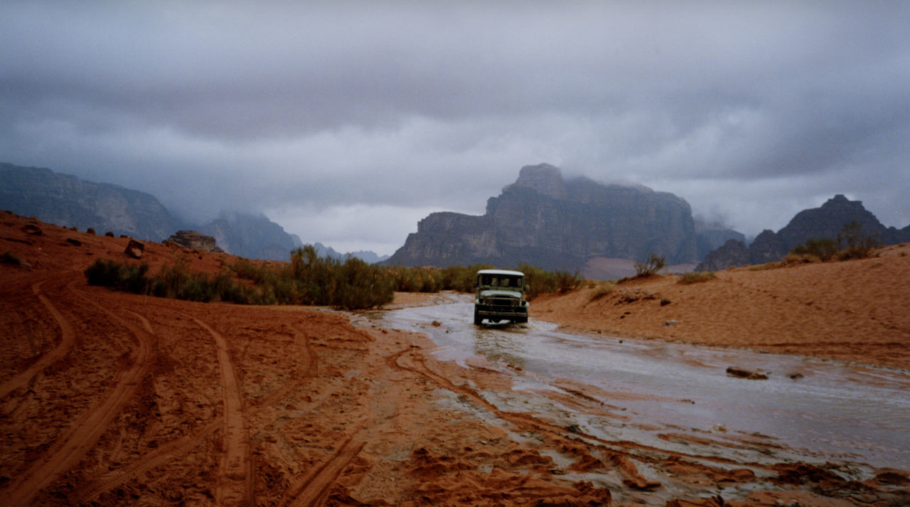 Off road vehicle on muddy road against cloudy sky