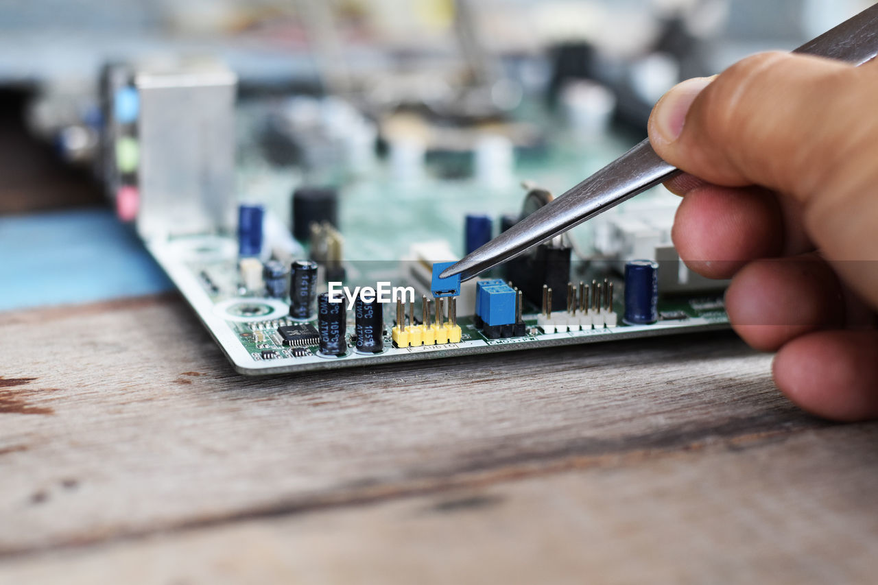 Cropped hand of technician repairing mother board at work shop