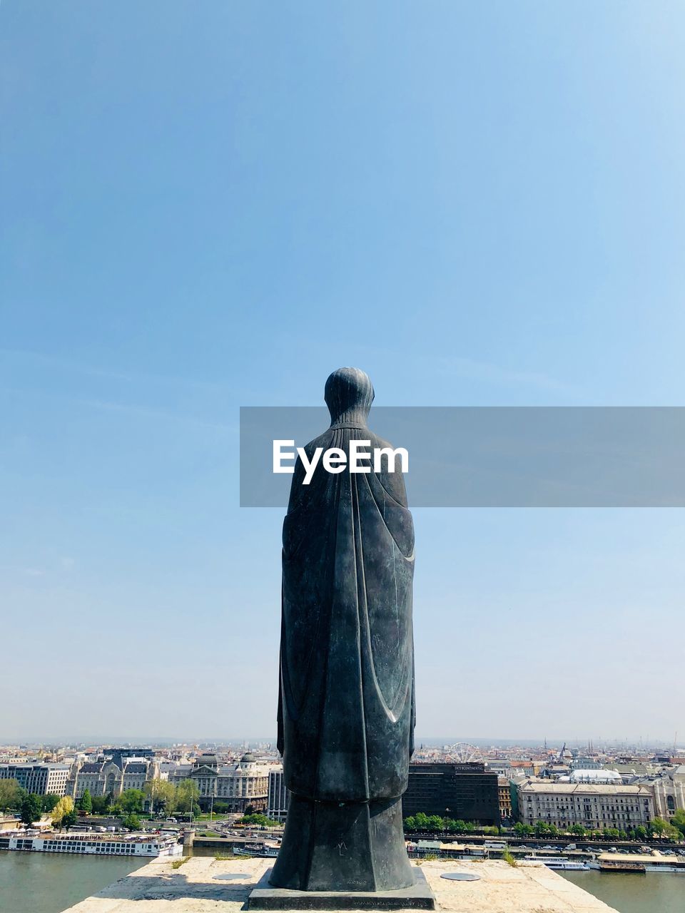Statue against cityscape and blue sky
