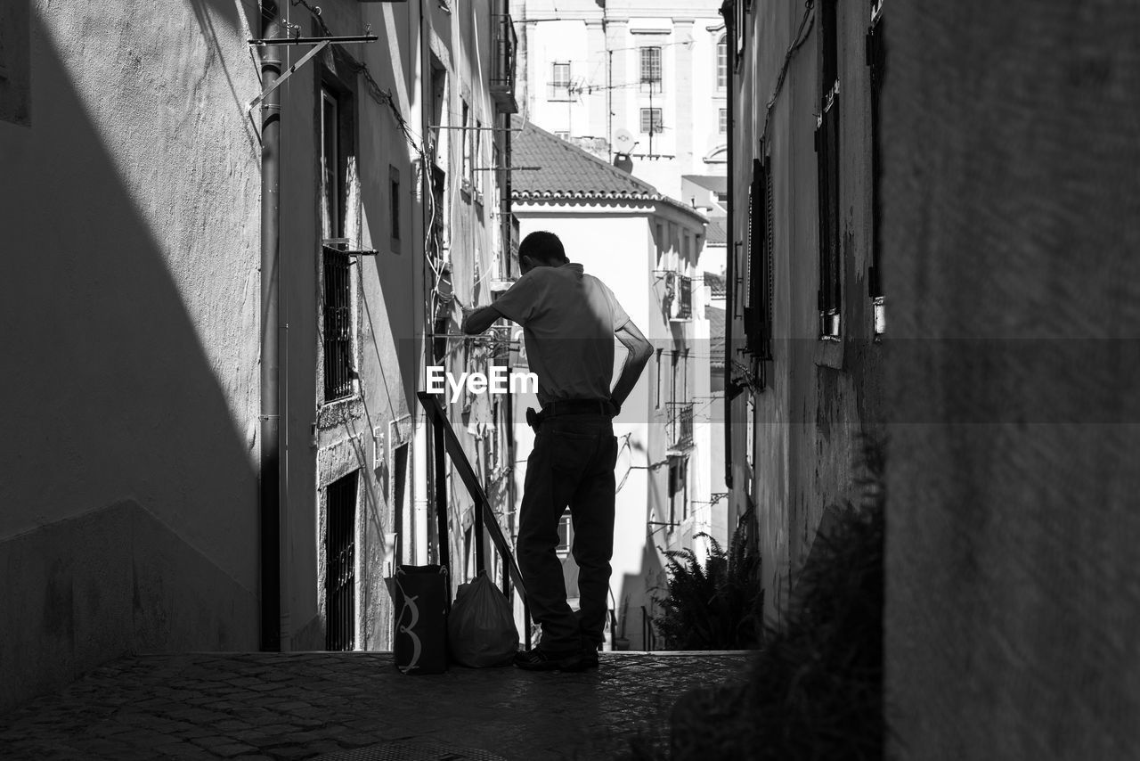 Man standing in alley amidst houses