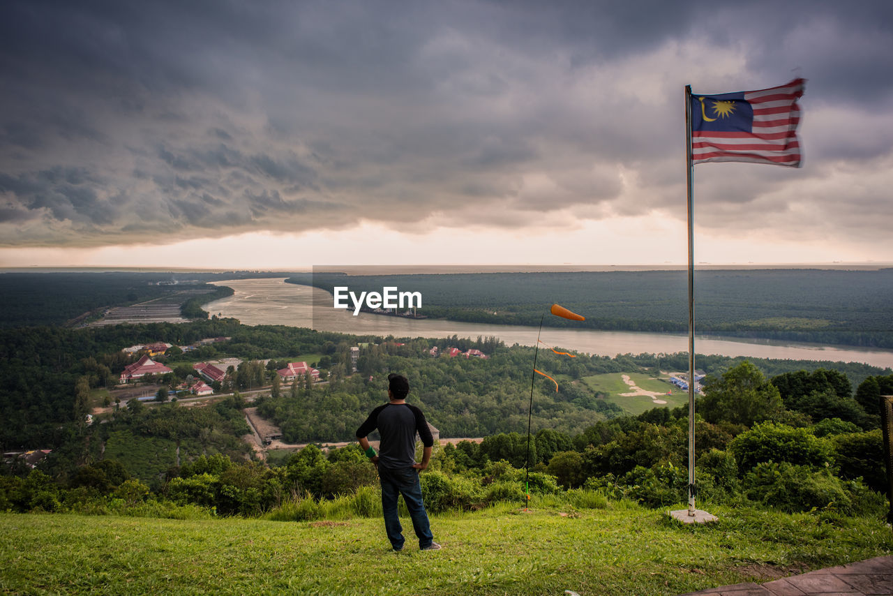 Rear view of man on mountain against cloudy sky