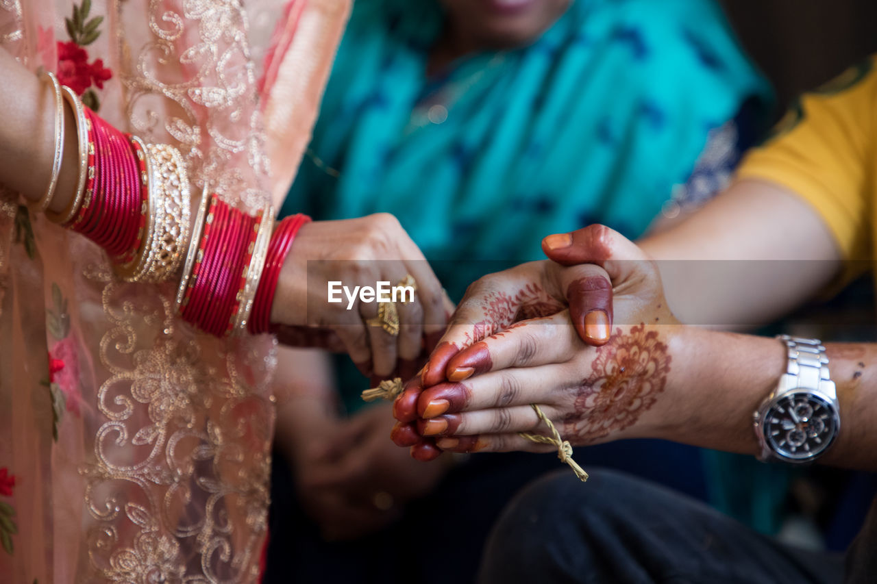 A woman putting haldi on groom's hand in an indian wedding