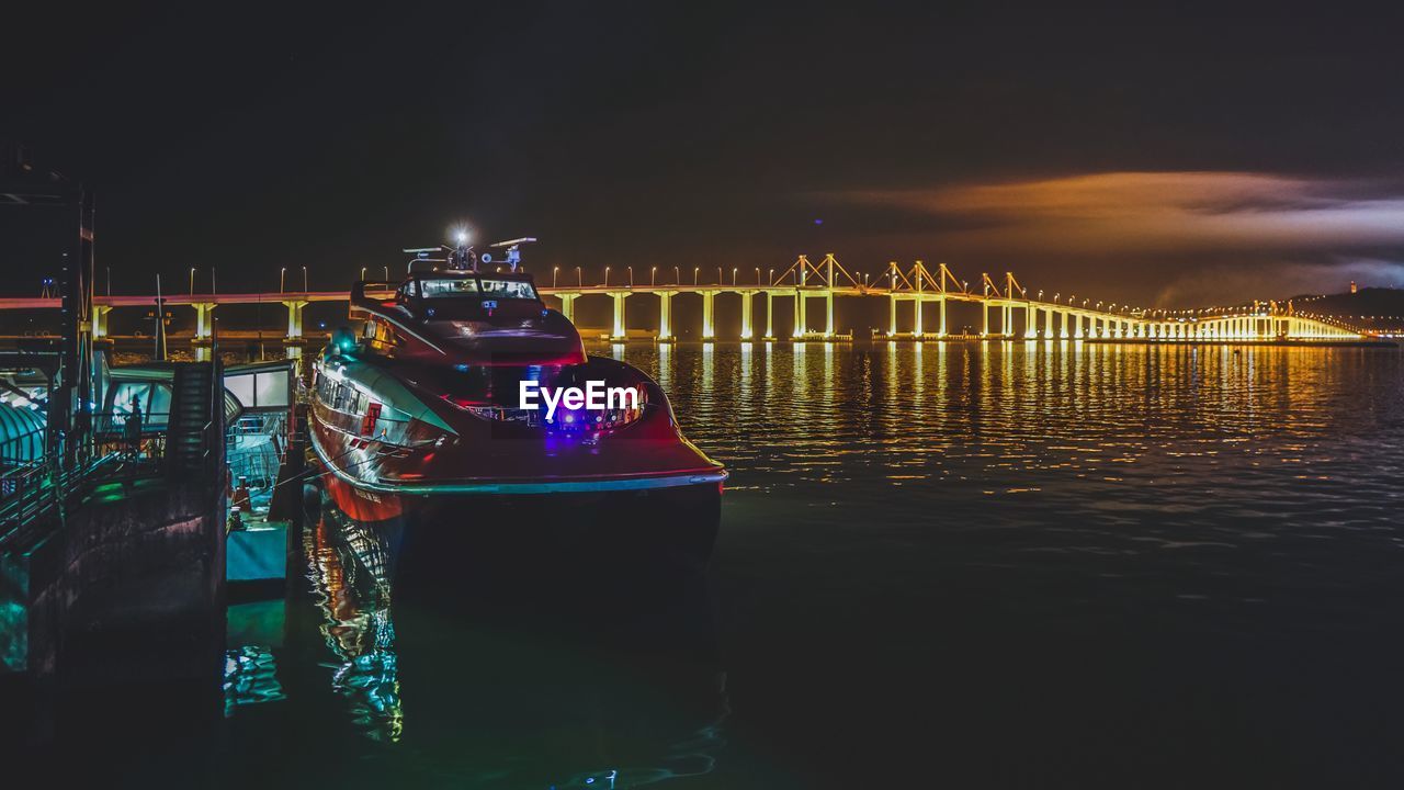 Illuminated bridge over calm sea at night
