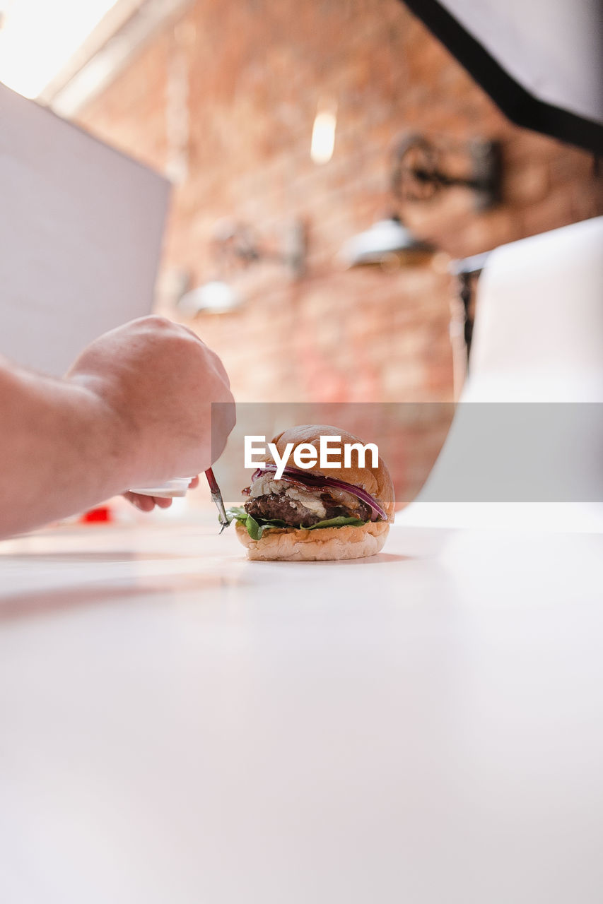 Close-up of hand preparing a burger