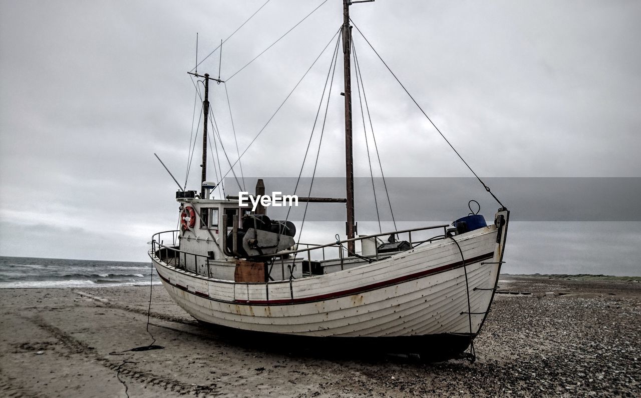 Boat moored on beach against sky