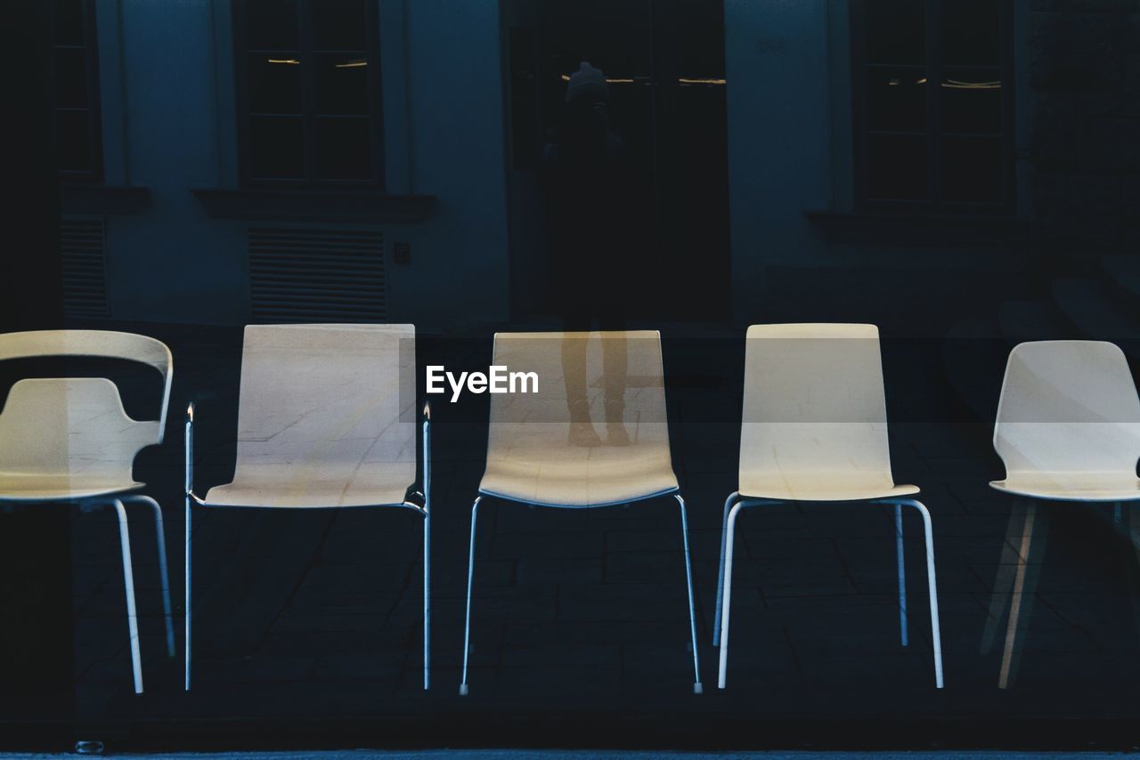 Empty chairs seen through glass window at store for sale