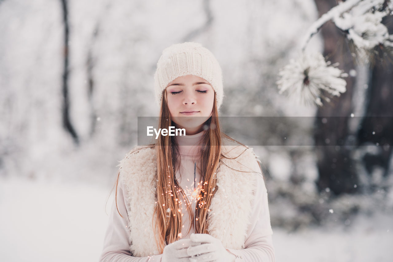 Teenager girl holding sparkler during winter