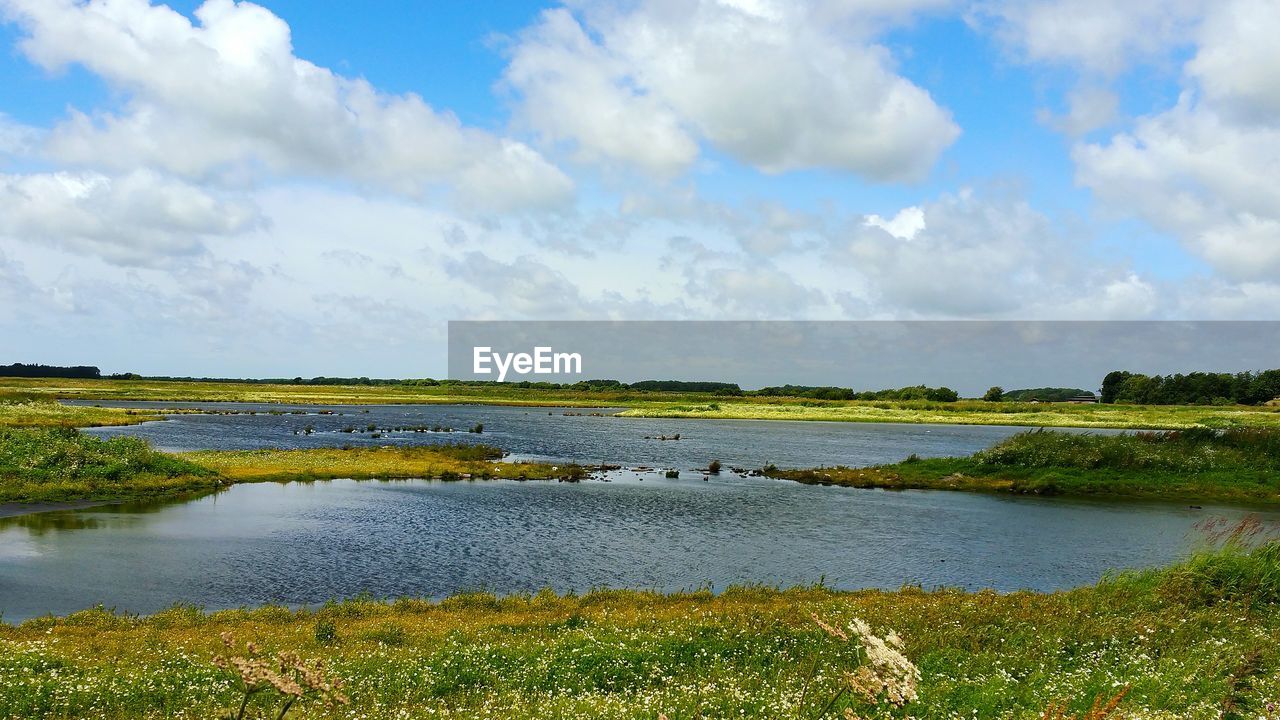 Scenic view of river against cloudy sky