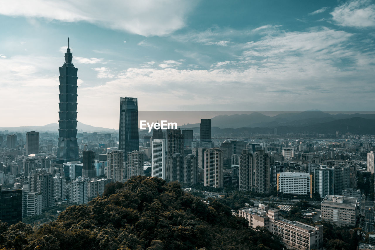 Buildings in city against cloudy sky