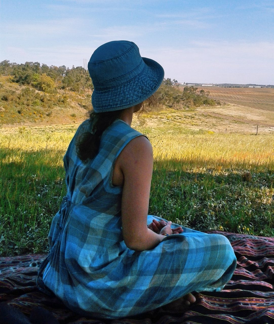 YOUNG WOMAN SITTING ON FIELD