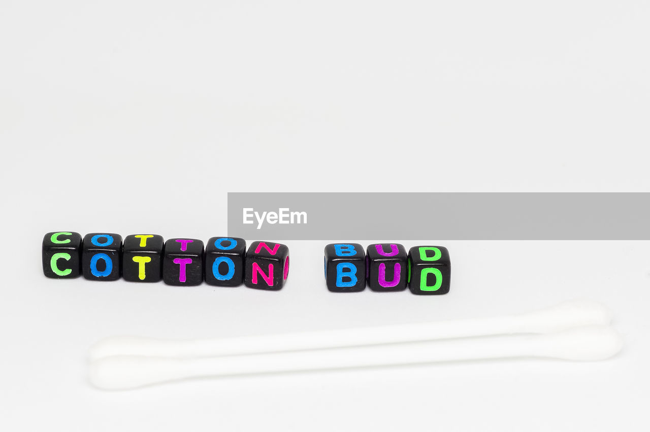 Close-up of cotton swabs and text over white background