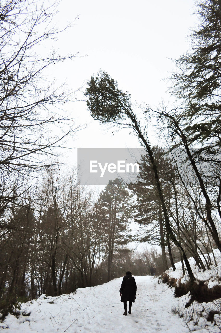 REAR VIEW OF WOMAN ON SNOW COVERED LAND