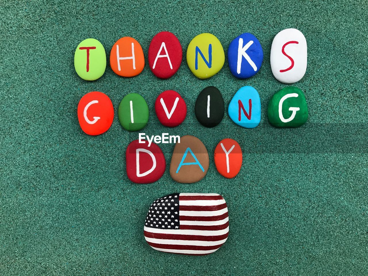 Directly above shot of colorful text on pebbles over sand