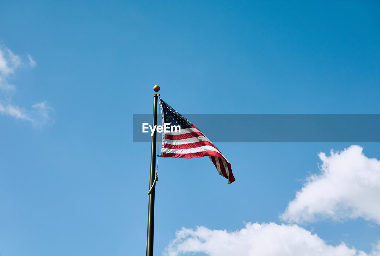 Low angle view of american flag against blue sky