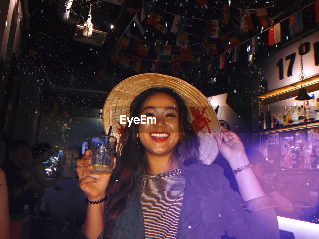 Portrait of smiling woman holding drink glass at bar