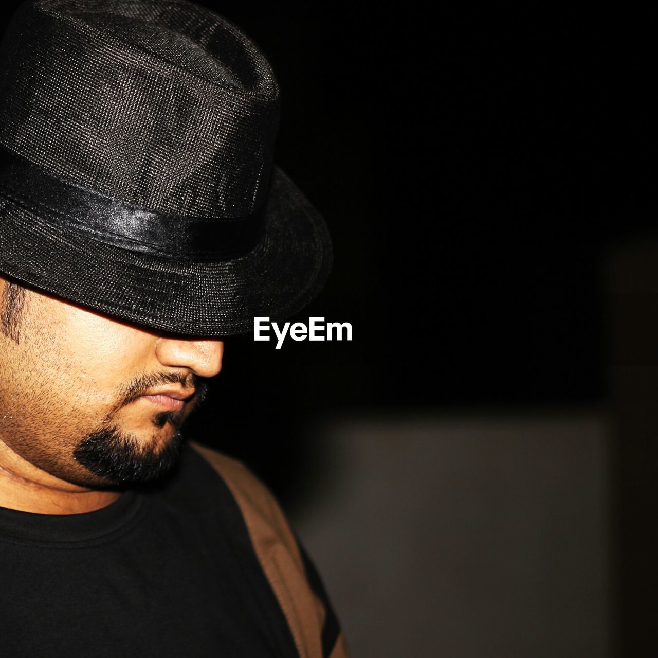 MIDSECTION OF MAN WEARING HAT AGAINST BLACK BACKGROUND