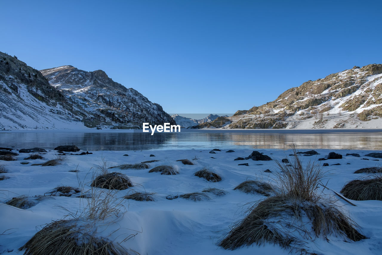 Scenic view of frozen lake against clear blue sky