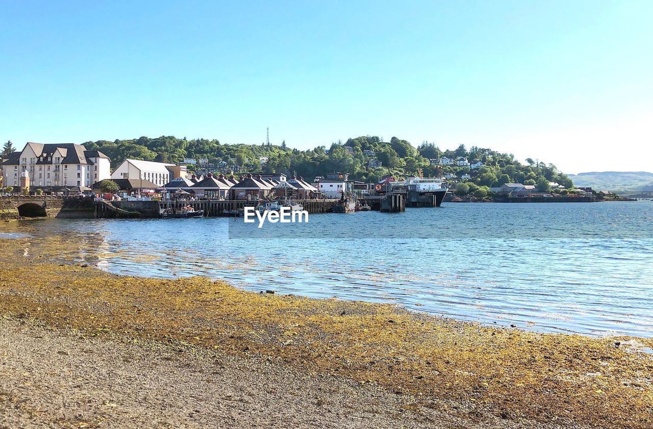 Scenic view of sea by buildings against clear sky