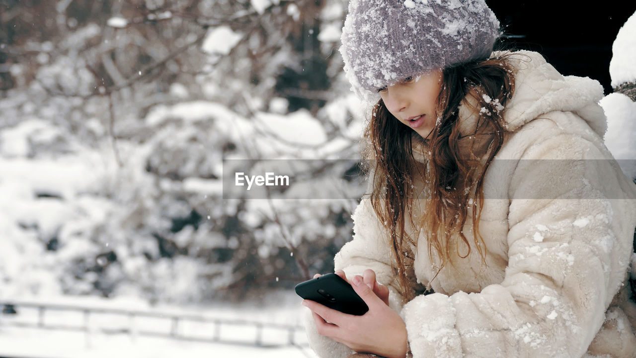 Winter portrait. cutie little girl, dressed in warm winter clothes, fully covered with snowflakes