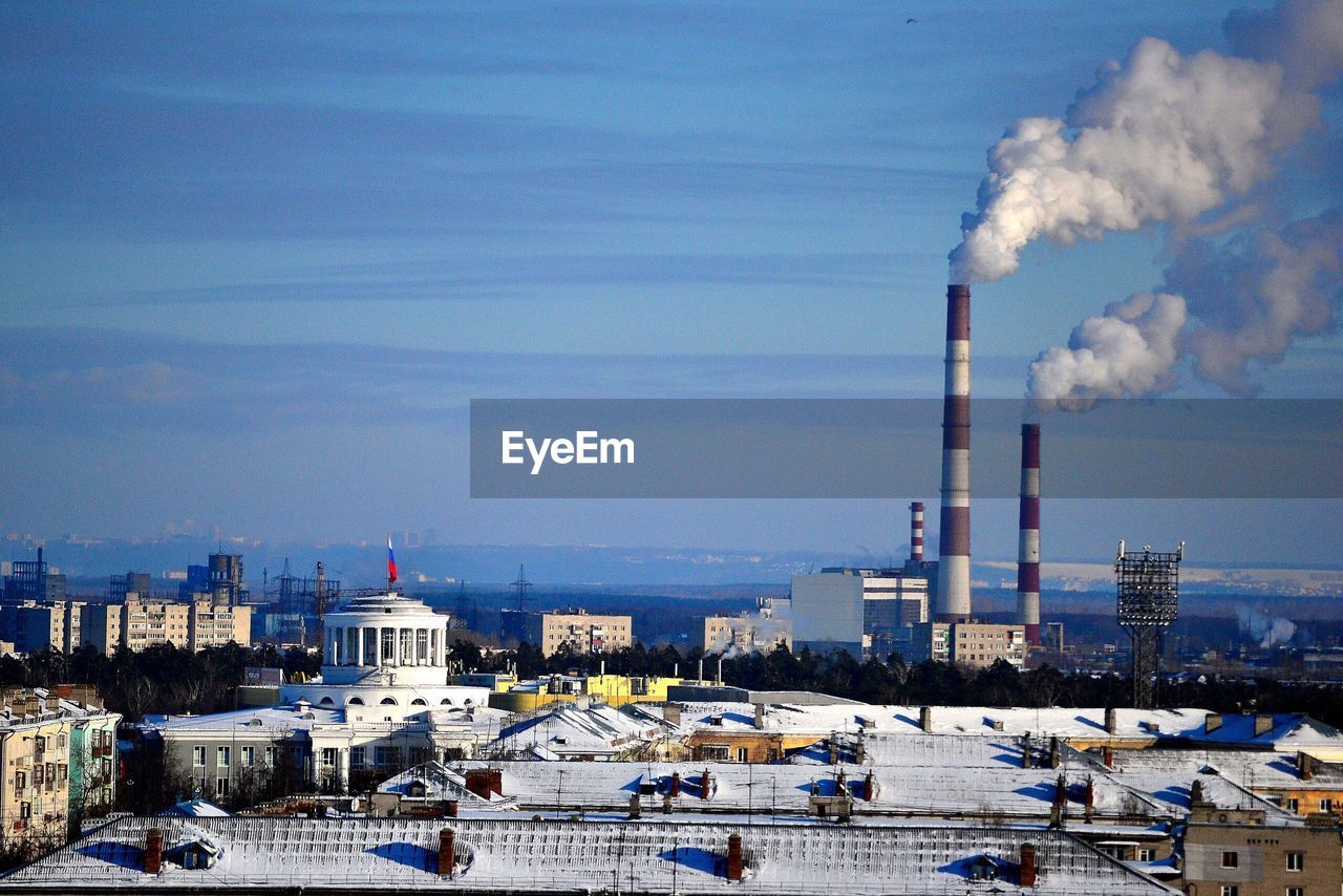 Smoke emitting from factory against sky