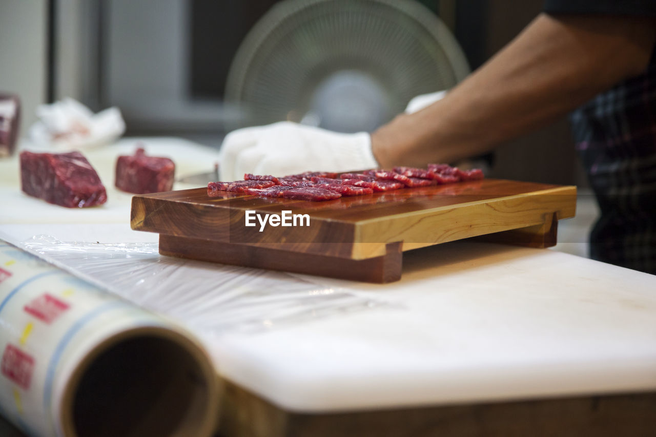 Midsection of man cutting meat in kitchen