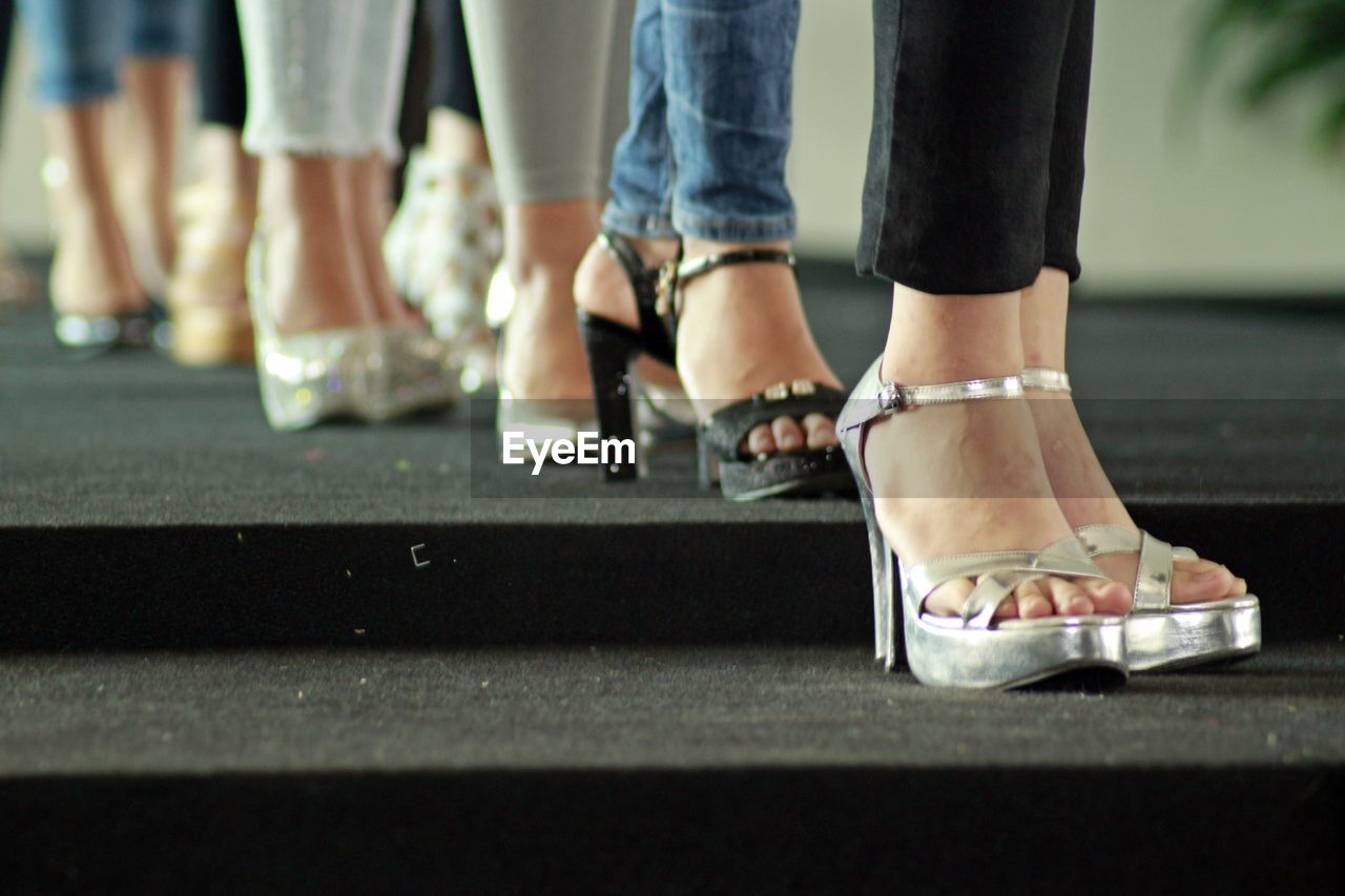 LOW SECTION OF WOMEN STANDING ON FLOORING