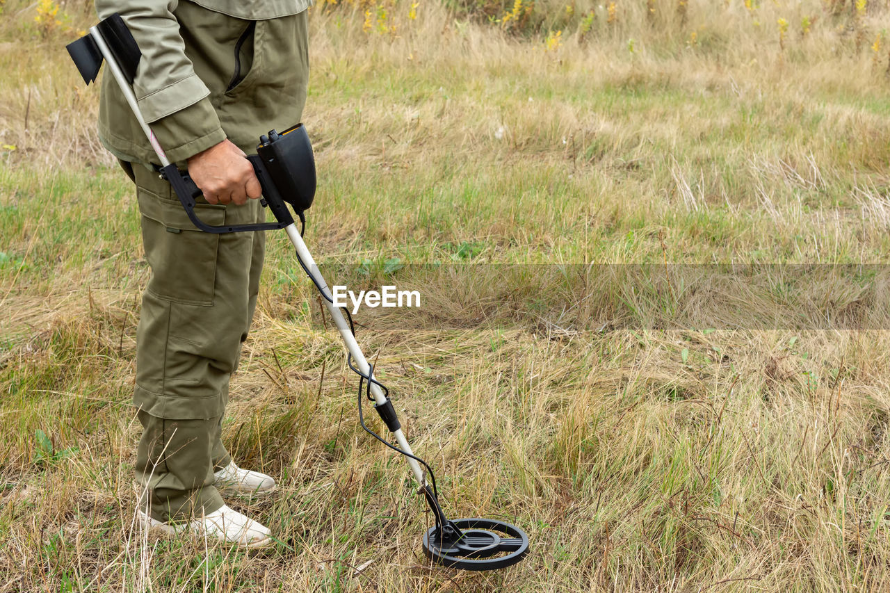 Man with electronic metal detector device working on outdoors.