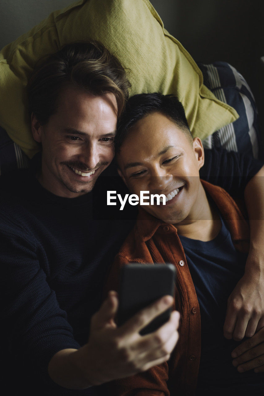 High angle view of smiling gay couple using smart phone at home