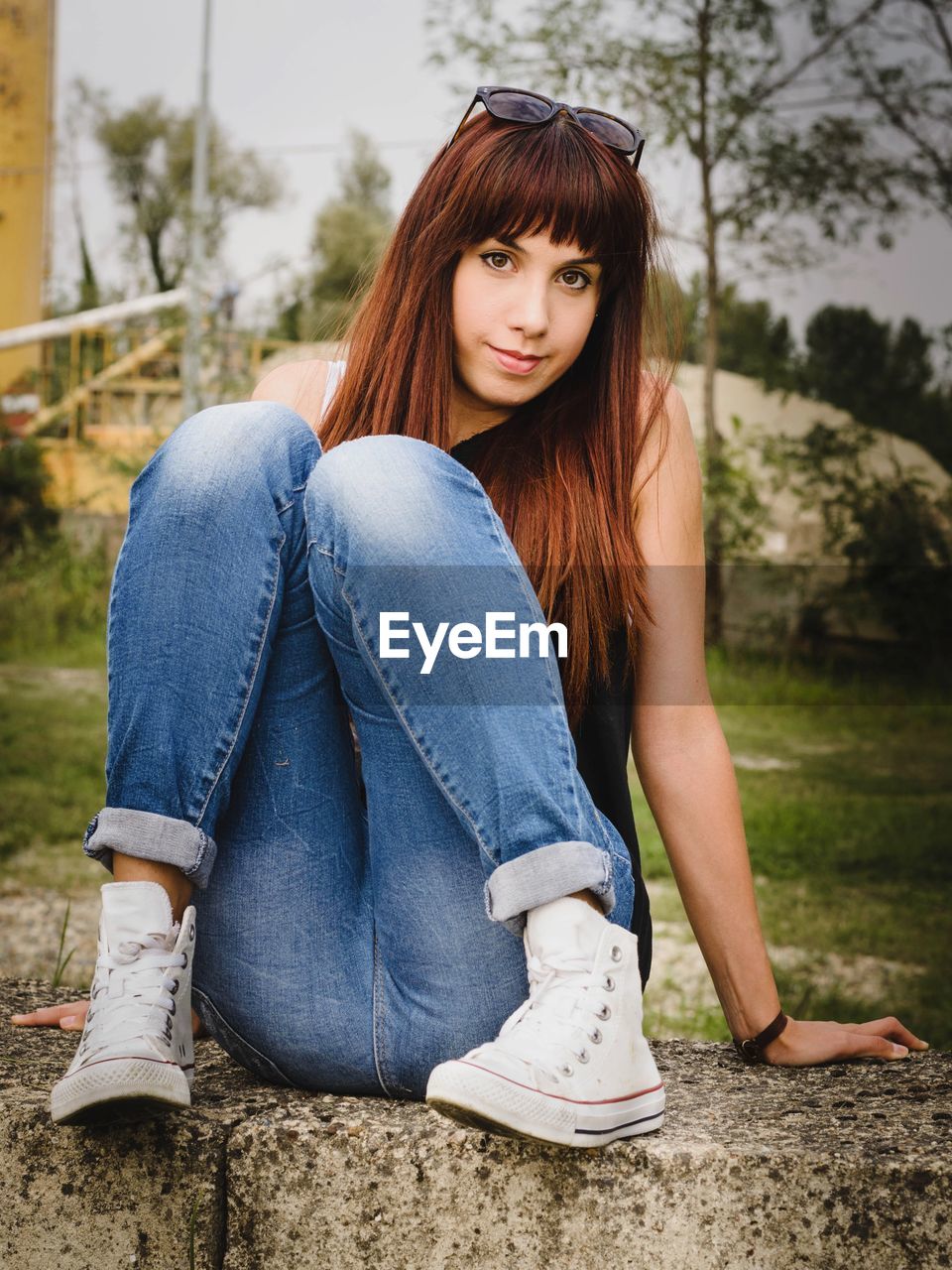 Portrait of woman sitting on retaining wall