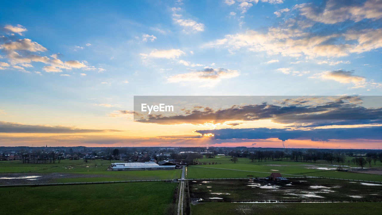 sky, cloud, horizon, environment, landscape, sunset, nature, scenics - nature, dusk, beauty in nature, grass, sunlight, land, water, architecture, plain, travel, evening, transportation, hill, field, no people, sports, outdoors, tranquility, plant, travel destinations, city, dramatic sky, blue, rural area, tranquil scene, rural scene, built structure, reflection, sea, cloudscape, road, mode of transportation, sun, tourism, horizon over land, building