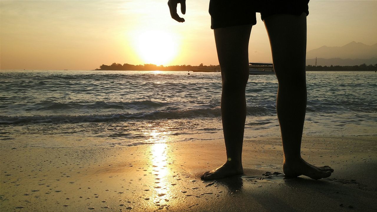 Low section of man standing on shore at gili trawangan beach