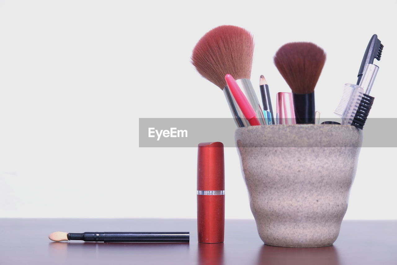 Close-up of make-up equipment on table against white background