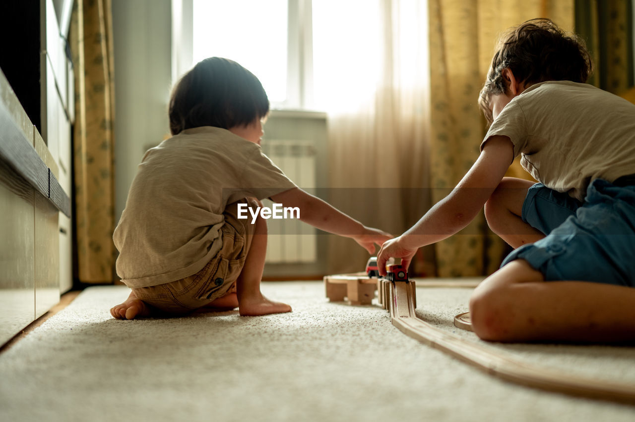 Two brothers play toys, they build a railway from a wooden construction set