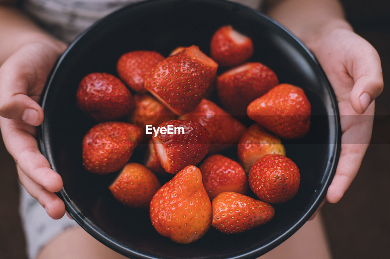 Ripe strawberries in a plate in children's hands. juicy red berries close up.