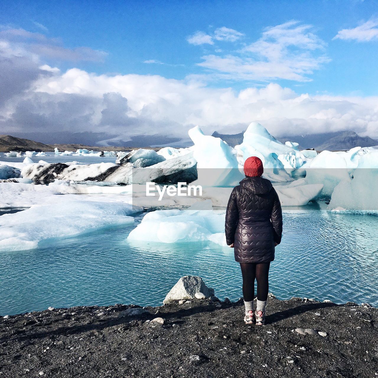 Rear view of woman standing in front of melting glaciers