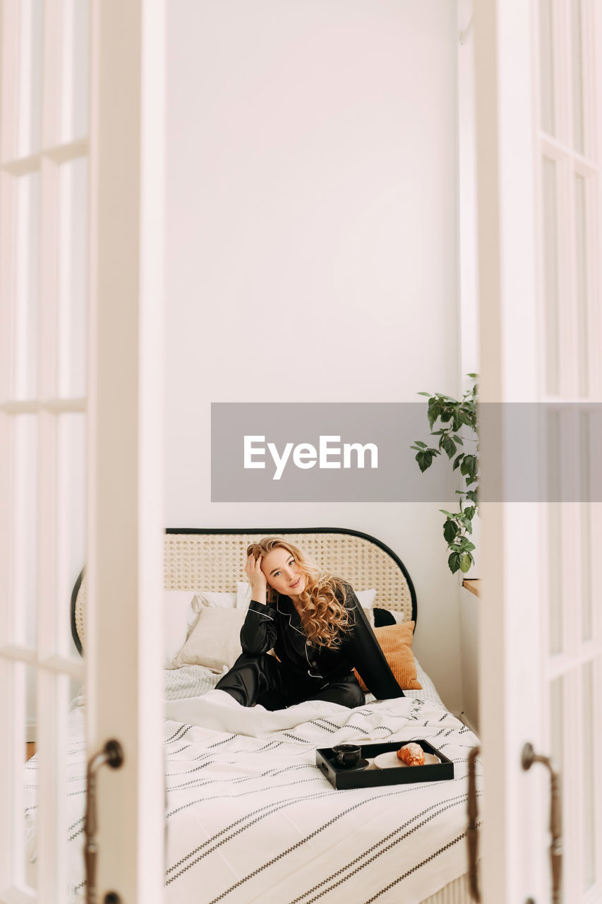 Beautiful happy smiling girl enjoying and having breakfast in bed in the morning in a cozy home