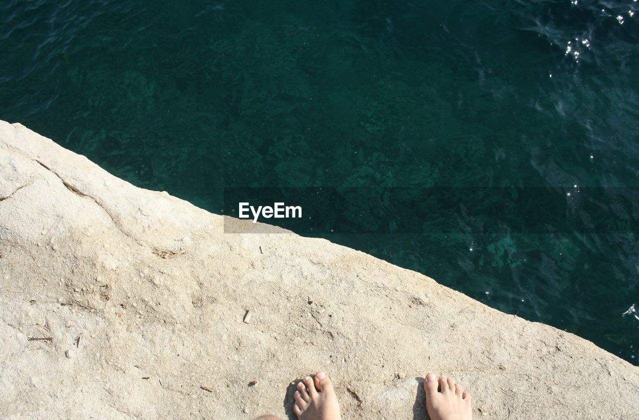 Low section of person on rock against sea