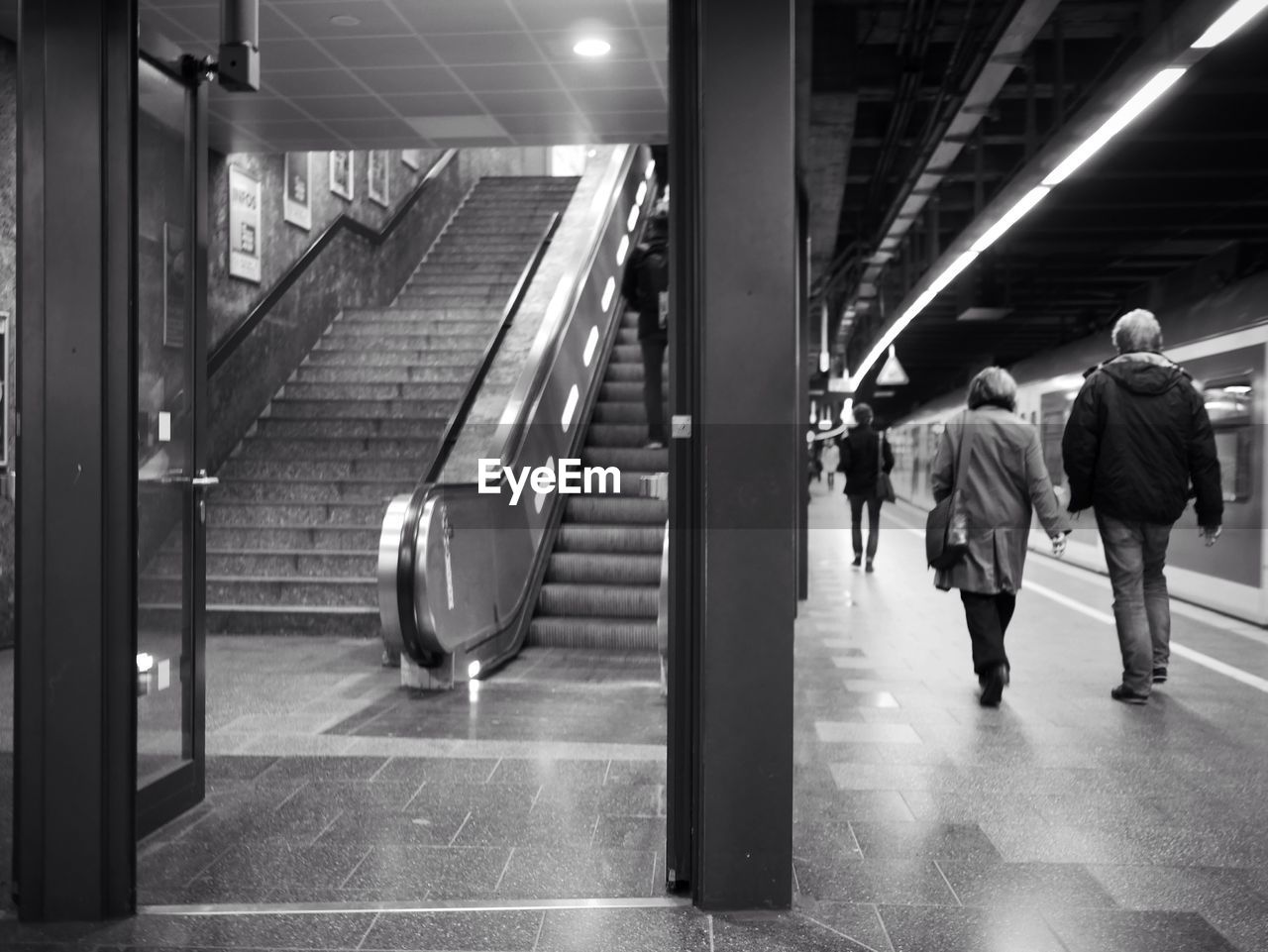 Full length rear view of people walking in underground subway station near steps