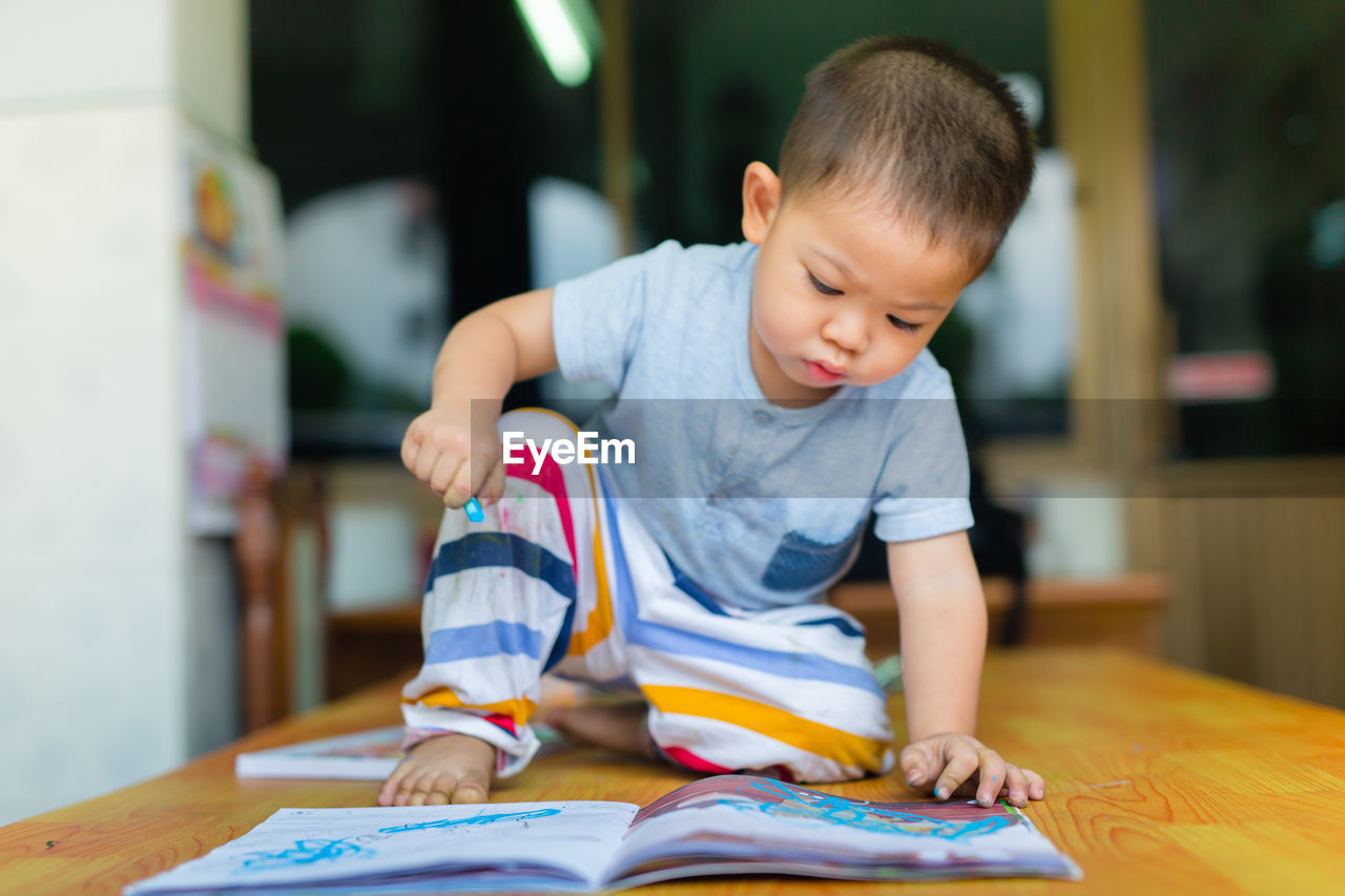 Boy drawing on book at table