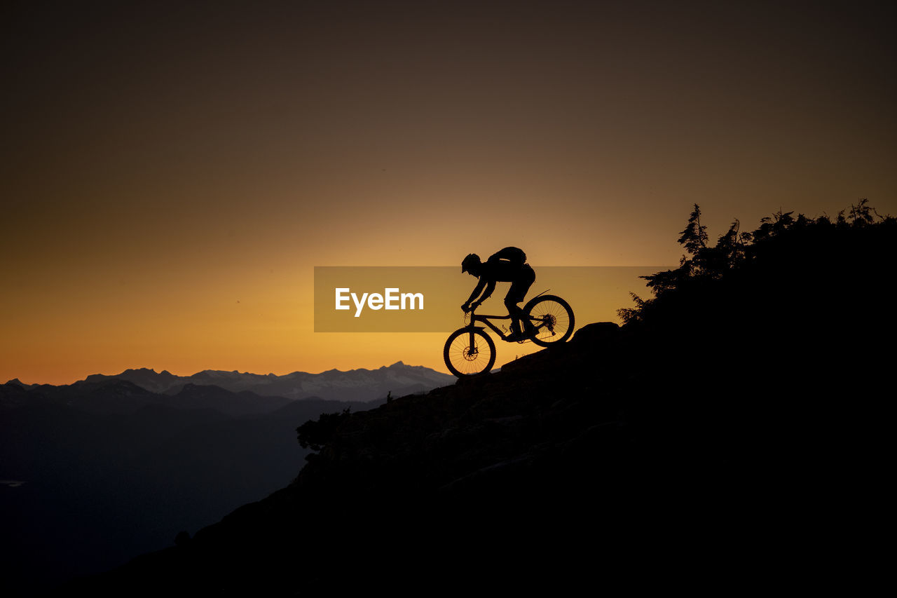 SILHOUETTE MAN RIDING BICYCLE AGAINST SKY