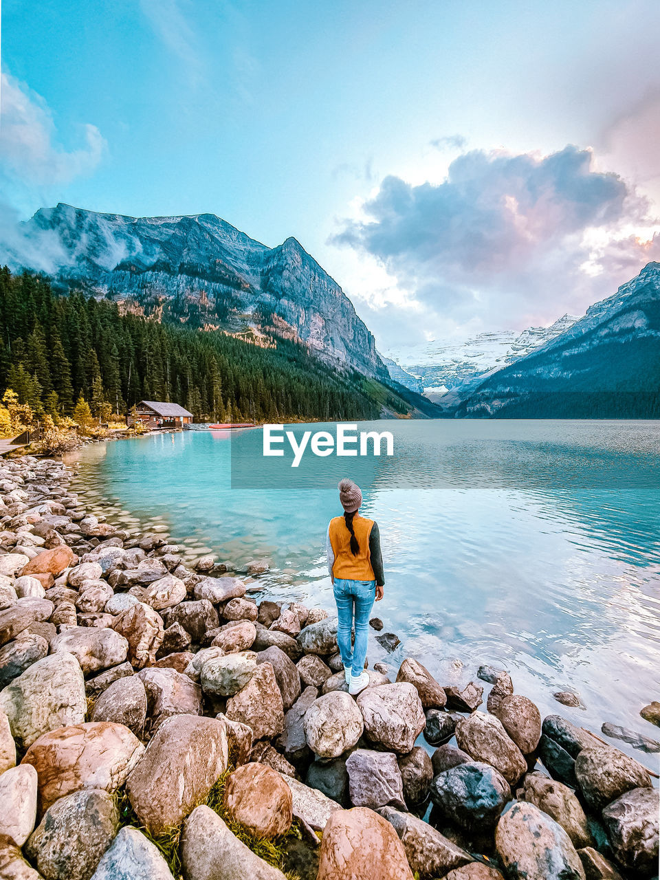 Rear view of woman standing by lake