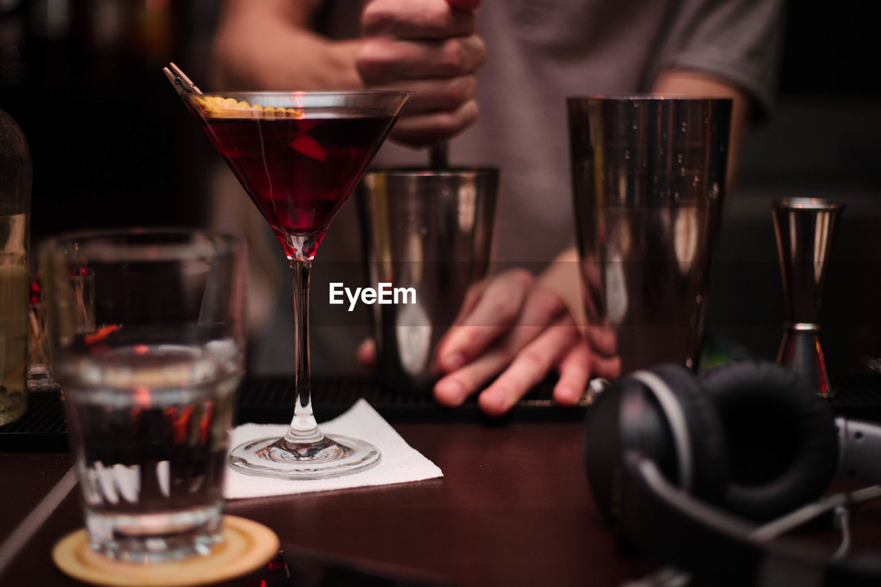 Midsection of bartender preparing drink at counter