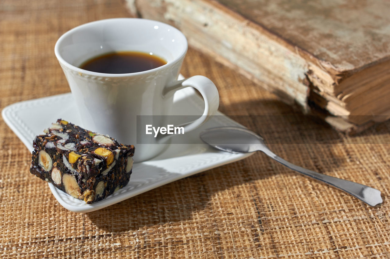 Turkish sweet with black coffee and old book on the wooden table.