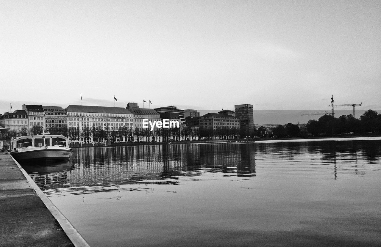 Lake and buildings against clear sky