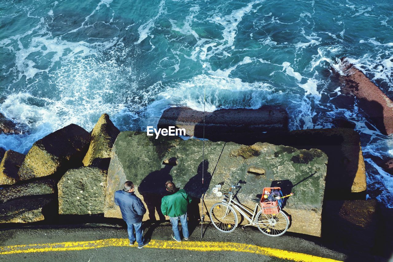 High angle view of men standing by sea