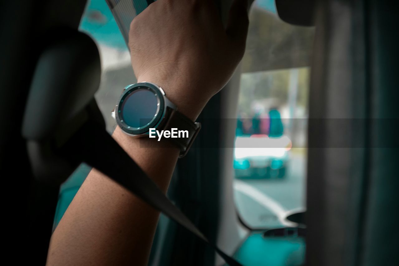 Cropped image of woman wearing wristwatch in car