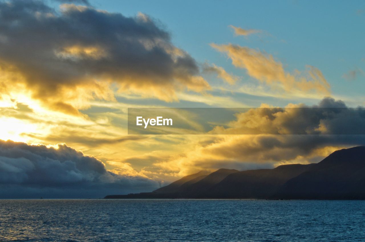 Scenic view of sea against dramatic sky during sunset